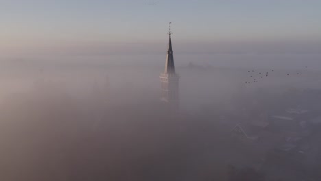 Cornwerder church at province Friesland in dense morning fog, aerial