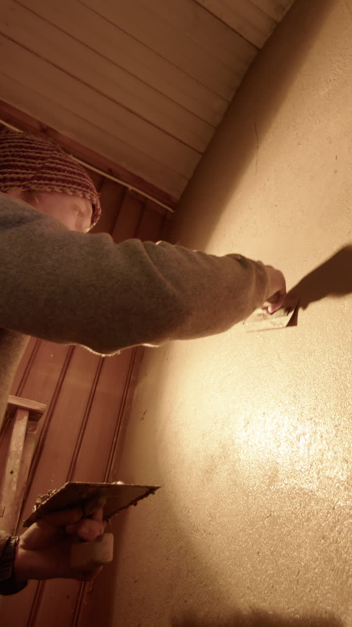 A handsome professional plasterer using a Japanese trowel to finish, vertical