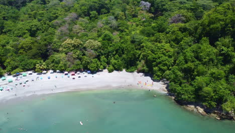 Aerial-panning-shot-of-tropical-tourist-beach-in-national-park-of-Manuel-Antonio,-Costa-Rica