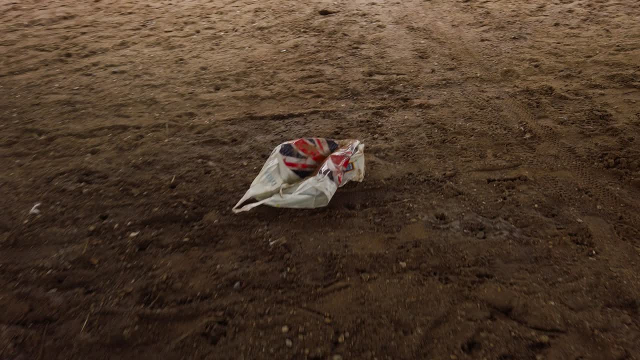 Carrier plastic bag on muddy sandy soil ground, environment pollution concept - handheld shot