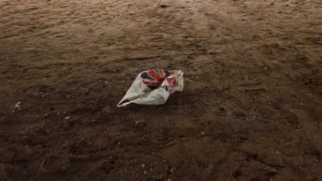 carrier plastic bag on muddy sandy soil ground, environment pollution concept - handheld shot