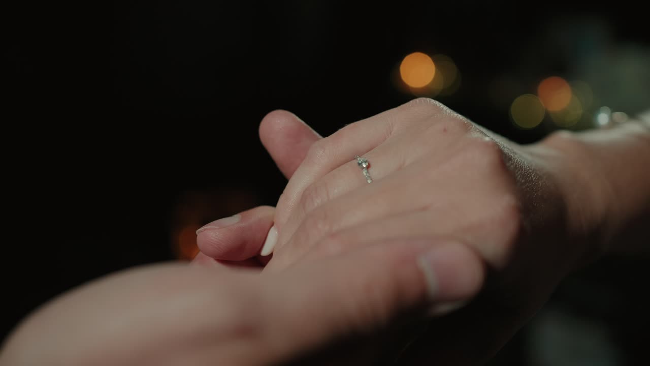 Close up of hands clasped together tenderly with soft lighting and blurred background