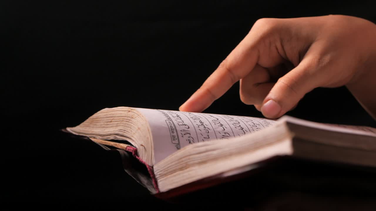 la mano de las mujeres musulmanas leyendo el corán por la noche