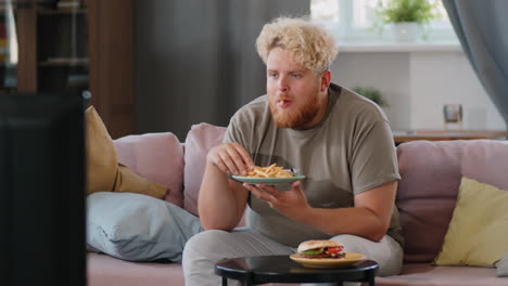 Obese-Man-Watching-TV-and-Eating-Fries-at-Home