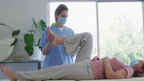 una trabajadora de la salud estirando la pierna de una mujer mayor en casa