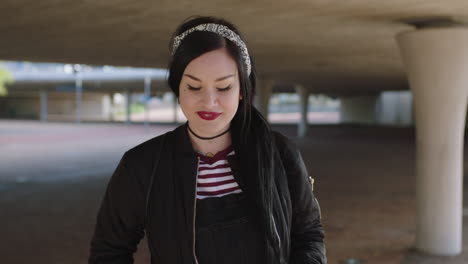 portrait-of-confident-alternative-young-woman-smiling-confident-at-camera-playing-with-hair-urban-background