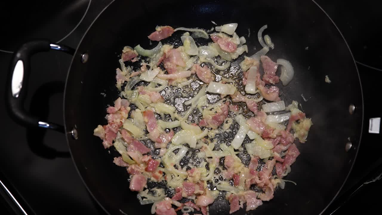 Close up shot of onions and meat crackles are cooking in hot pan with hot and bubbling oil