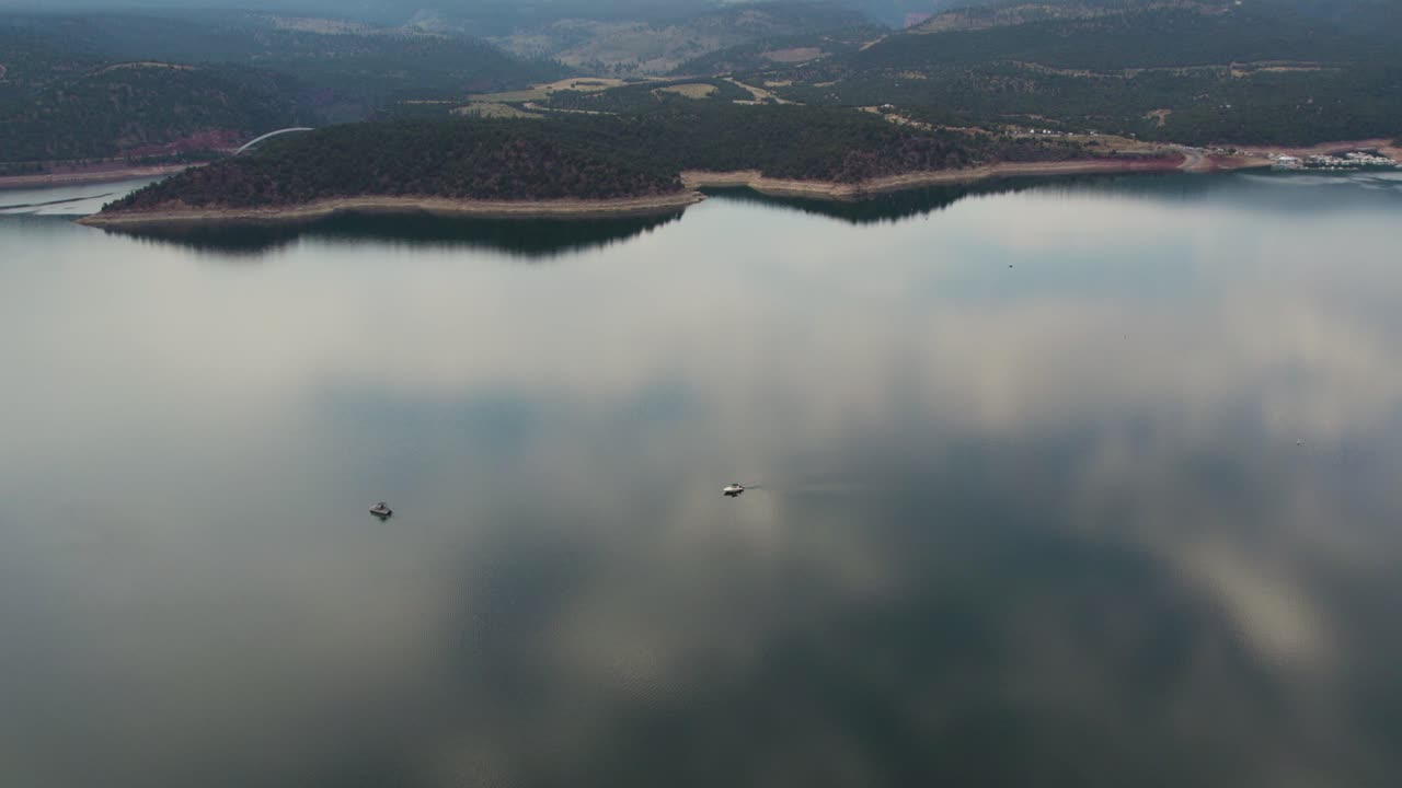 미국 와이오밍 주 불타는 협곡 저수지에서 보트와 반사가 있는 호수의 잔잔한 물 - 공중 드론 샷