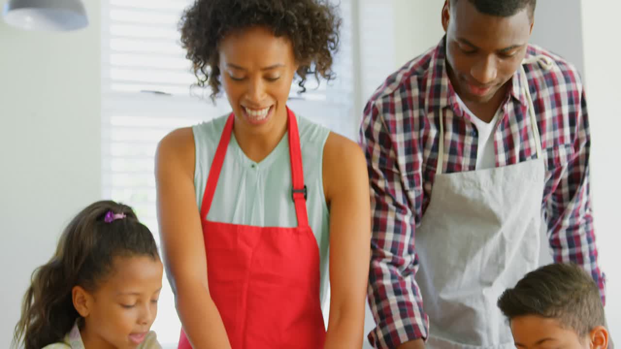 vista frontal de una familia negra usando un cortador de galletas en la cocina en casa 4k