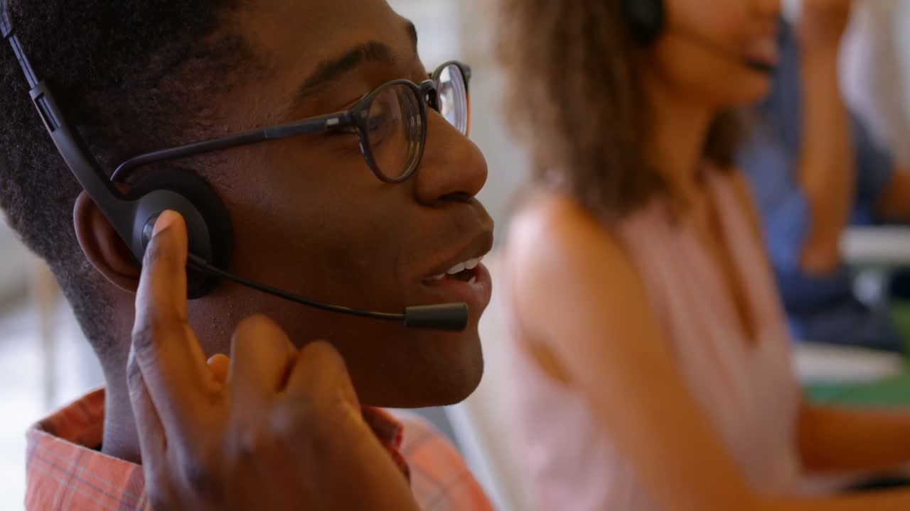 Side view of African American male executive talking on headset at desk in the office 4k