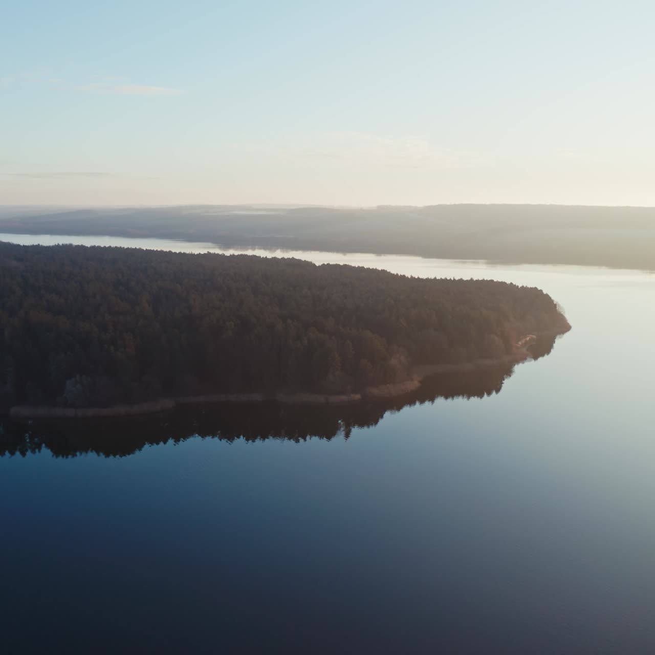 Beautiful view of nature. Wide river with blue calm water in the evening. Small island surrounded by water. Aerial view.