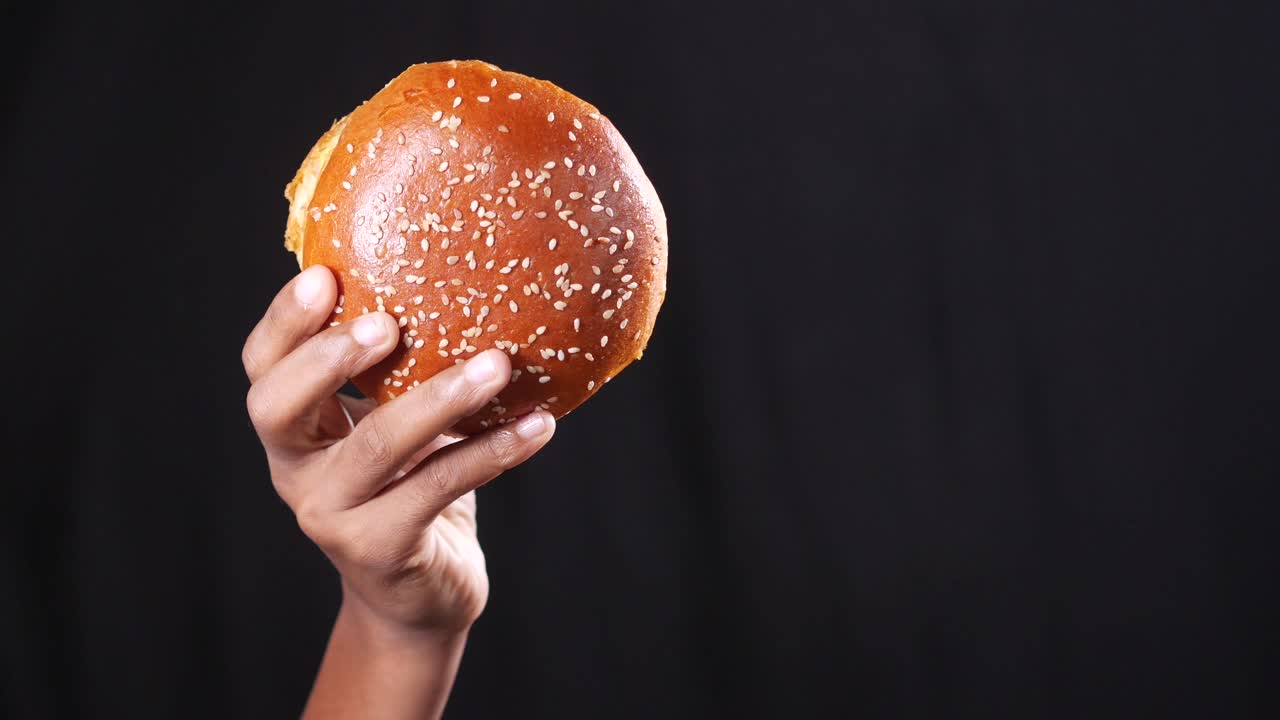 Hand holding a sesame seed bun