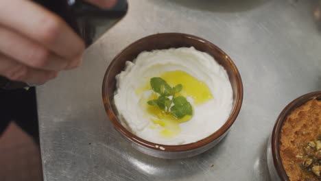 chef plating mediterranean starter yogurt dish, adding olive oil on top