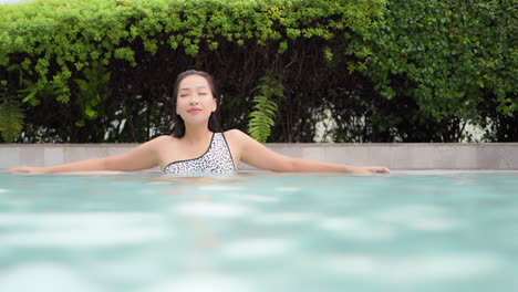 an attractive woman lounges in the shallow water of a resort swimming pool