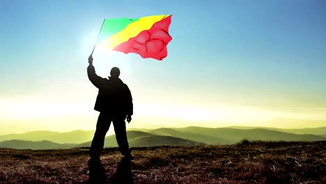 exitoso hombre silueta ganador agitando la bandera de la república del congo en la parte superior del pico de la montaña. fondo de bucle cinemagraph