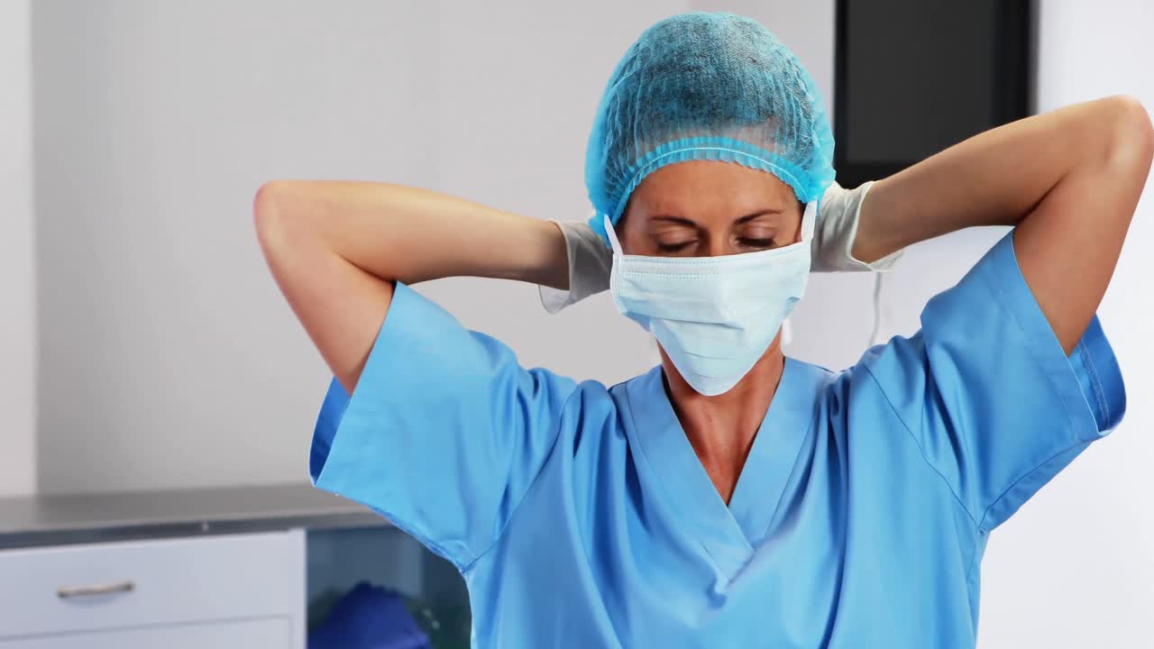 enfermera atando una máscara quirúrgica en el quirófano