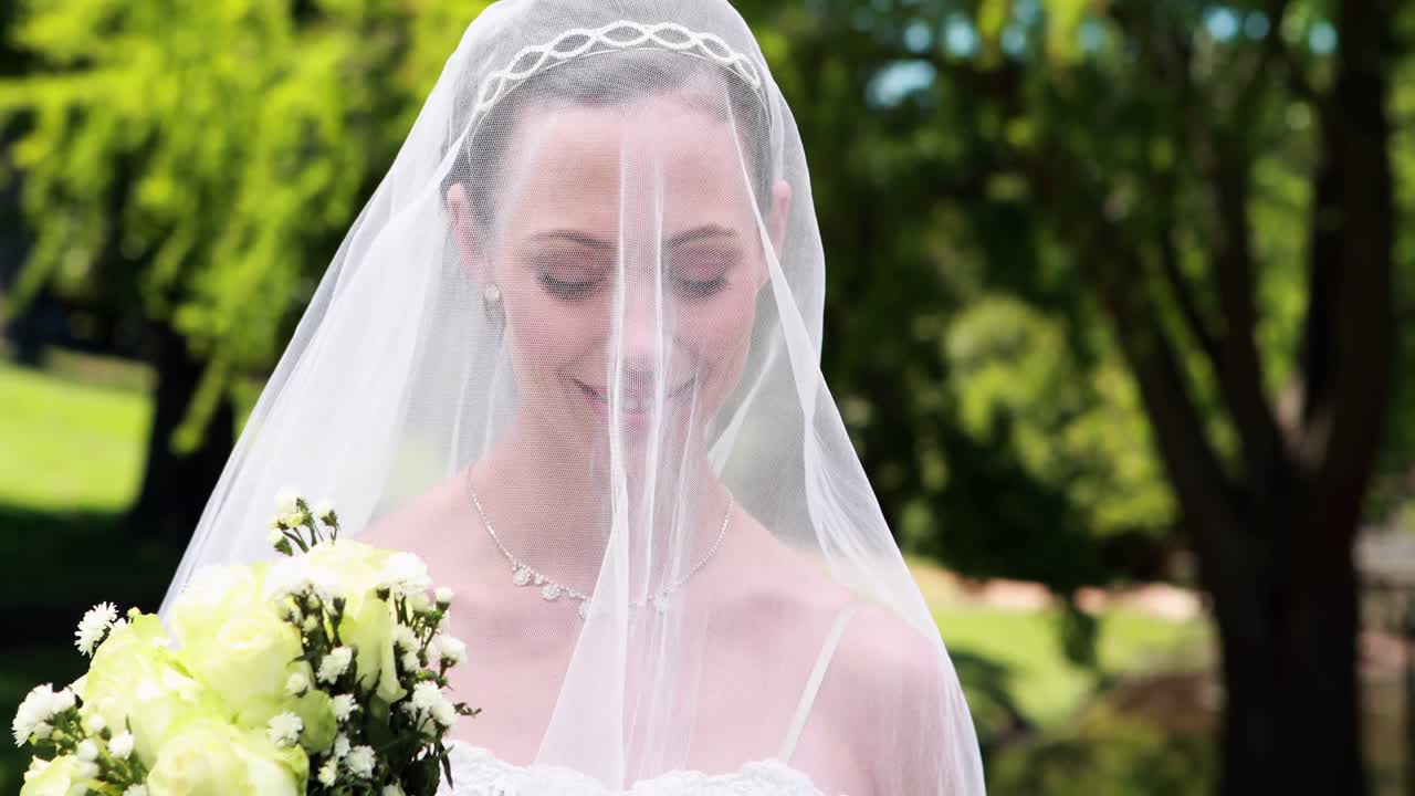 Bella sposa che sorride alla fotocamera con il velo sul viso