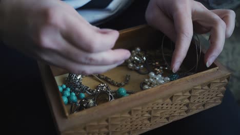 close-up of the hands of a girl who is digging in a box with jewelry and other valuables. shooting close up