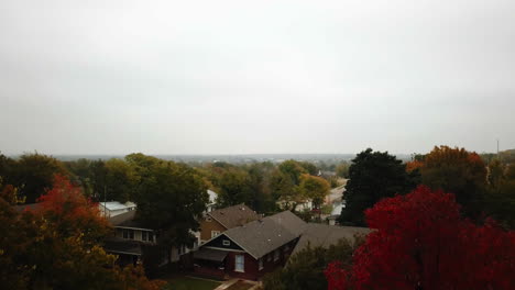 Descending-aerial-shot-above-a-residential-area-revealing-the-vibrant-autumnal-colours-on-the-trees