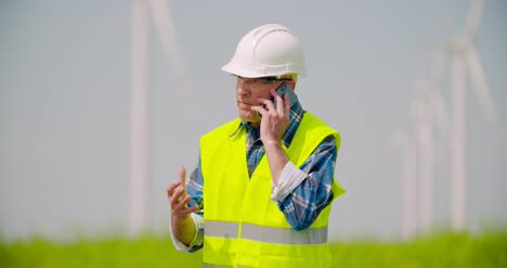 Ingeniero-Enojado-Hablando-Por-Teléfono-Móvil-Contra-Molinos-De-Viento-Granja-6