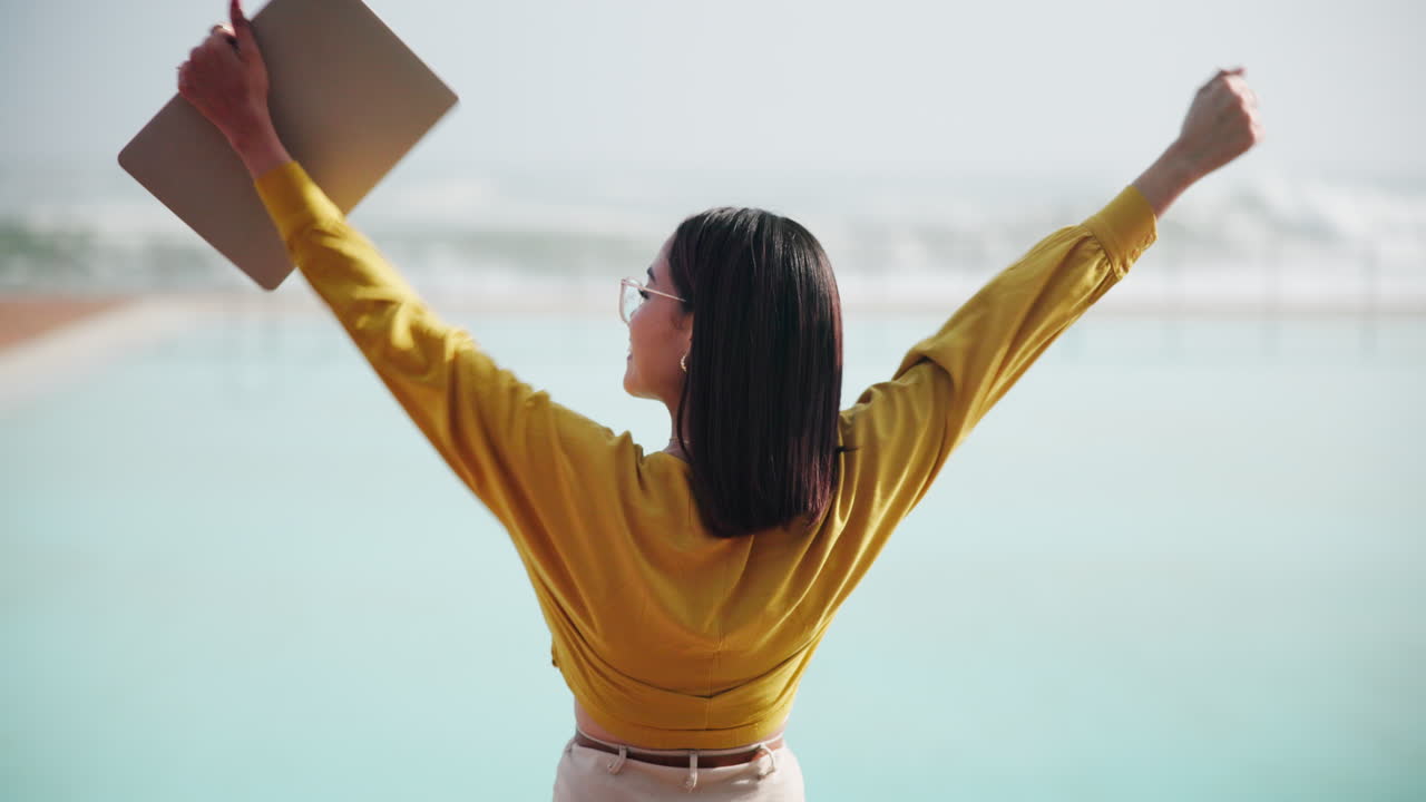 Woman celebrating success with laptop on beach