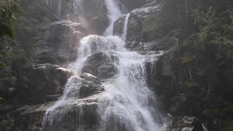 Nahaufnahme-Eines-Zwischen-Bäumen-Eingebetteten-Bergwasserfalls-In-4k