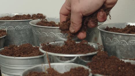 the soil is being dispersed across the buckets, as it is sprinkled or scattered evenly into each one