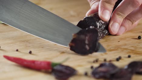 slicing a dark sausage on a wooden board