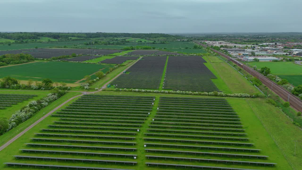 Aerial Footage of Photovoltaic Panels and Passing Train Near Solar Energy Plant in the UK Countryside