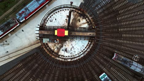 yellow and red locomotive leaving the railway turntable in the depot