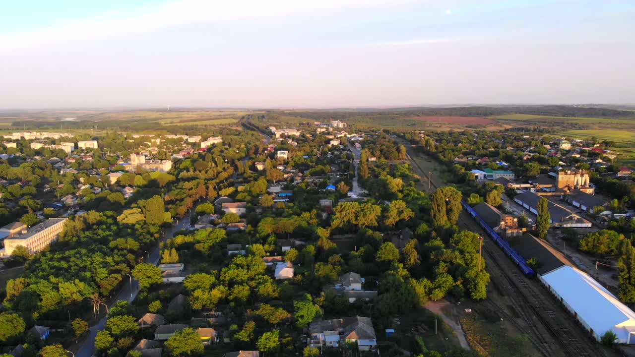 Aerial drone shot of Donduseni city with multiple residential buildings and greenery and fields. Sunset in Moldova