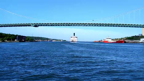 A-ferry-passes-under-the-Alvsborgsbron-bridge-in-Gothenburg,-Sweden