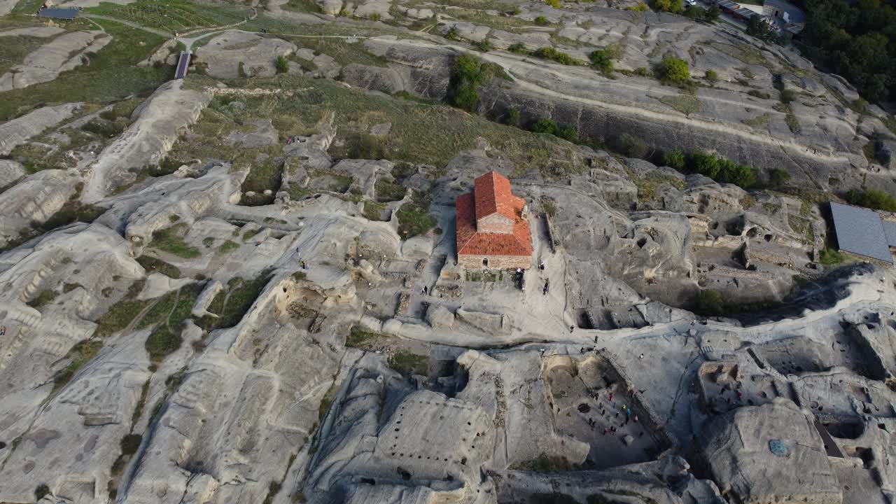 Aerial of Uplistsikhe cave city and stone structures under cloudy sky in Georgia