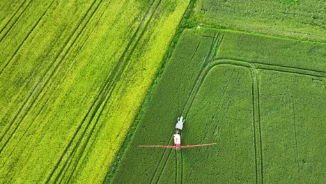 Toma-Aérea-De-Arriba-Hacia-Abajo-De-Un-Fumigador-Rociando-Un-Campo-Verde