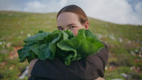 meisje met groene koolbladeren in handen close-up. glimlachende boer kijk camera