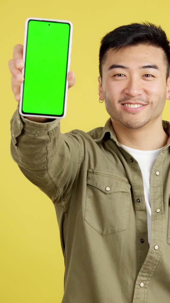 Asian man showing a smartphone with a green screen