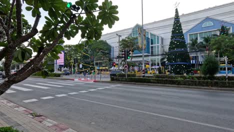 vehicles moving past a decorated mall and trees