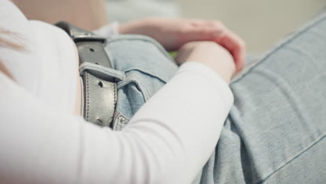 close up of woman in ribbed white top and denim trousers swinging outdoors, hands rest gently on lap as she relaxes in soft sunlight, subtle motion and clothing texture emphasize calm leisure