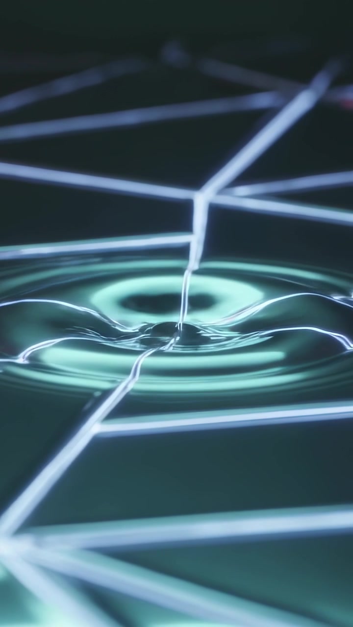 Video verticale: Goccia trasparente che cade formando una corona e increspature su una griglia al neon, con filamento che si alimenta.