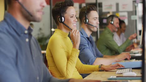 pessoas de negócios felizes e diversificadas sentadas à mesa e usando fones de ouvido no escritório