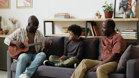 black man playing ukulele for family at home