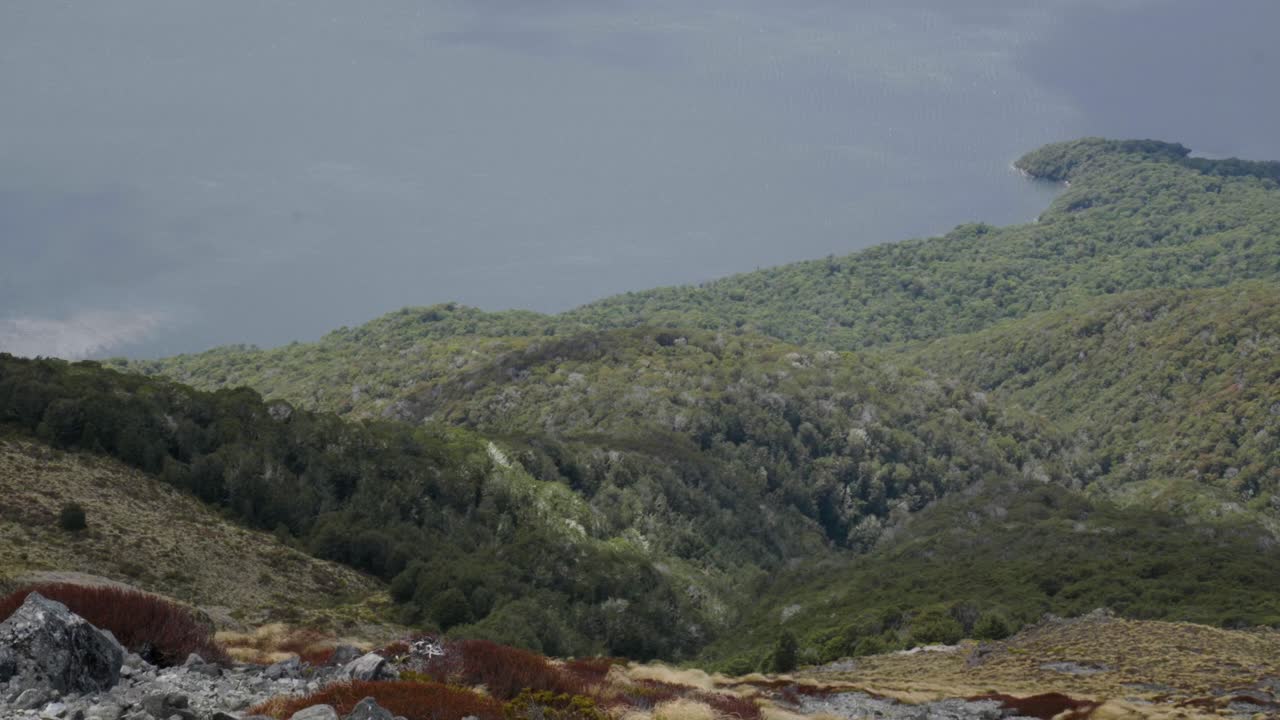Breathtaking view of a lake from high on a mountain, revealing vast water below, layered landscapes, and a peaceful sense of height and scale