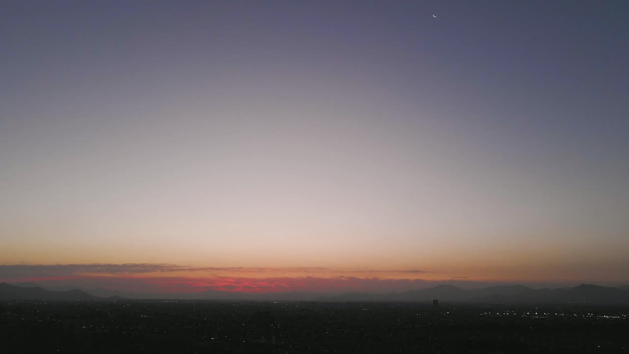 Aerial view at Santiago de Chile with the mountains and the moon in the background in the middle of the sunset