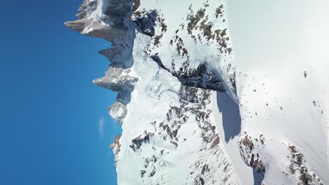 Disparo-Vertical-De-Drones-Que-Muestra-Montañas-Cubiertas-De-Nieve-En-La-Patagonia-Contra-El-Cielo-Azul,-Argentina---Toma-Panorámica-De-La-Montaña-Fitz-Roy