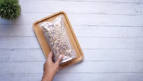 person holding a bag of oatmeal on a wooden tray