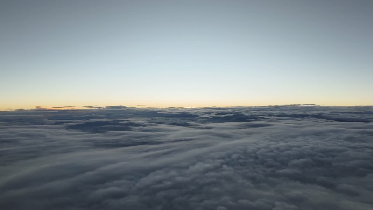 Aerial sunset recorded from a jet cockpit flying over a layer of stratus clouds and crossing it during descend. Right side view. 4K. Hyper lapse.