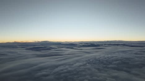 aerial sunset recorded from a jet cockpit flying over a layer of stratus clouds and crossing it during descend. right side view. 4k. hyper lapse.