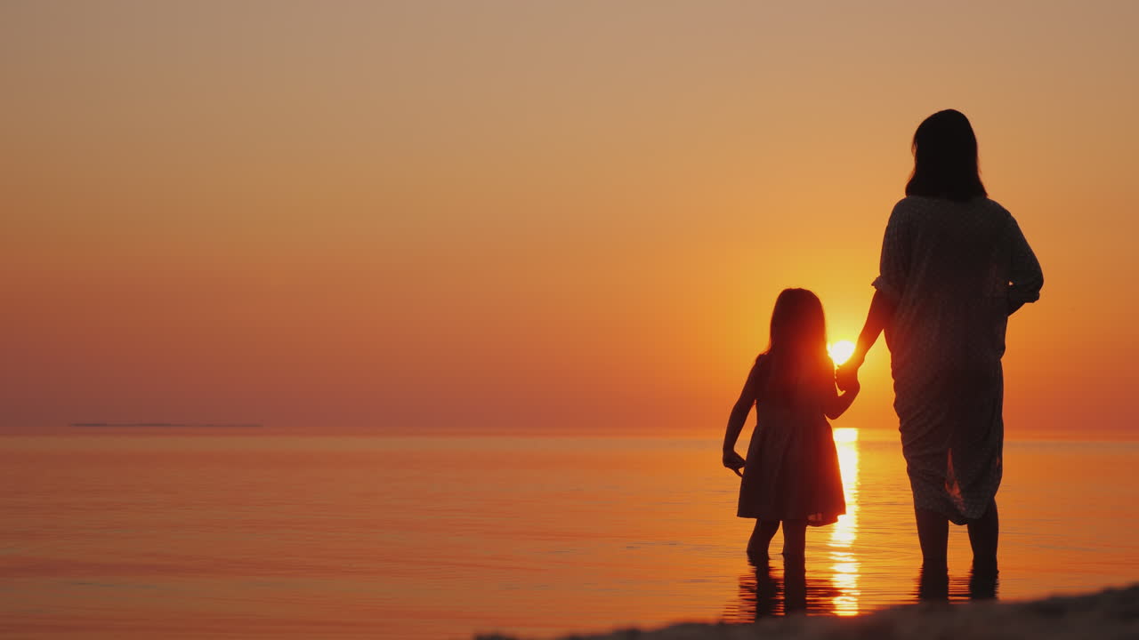 silueta de una mujer embarazada con un bebé cerca de pie cerca del mar al atardecer esperando el seco
