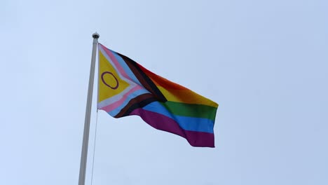 pride flag waving with grey sky in background. pride month concept