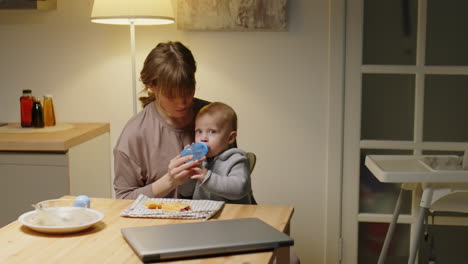 baby boy drinking water and eating pastry with mom